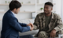 a veteran in a camouflage uniform shaking hands with a psychologist.